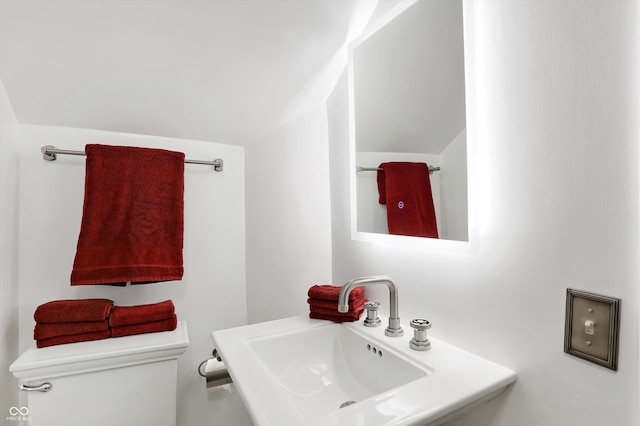 bathroom with lofted ceiling, a sink, and toilet