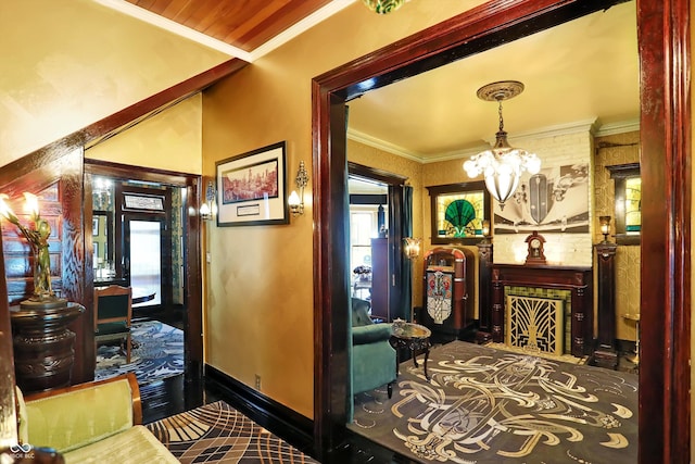 hall featuring baseboards, ornamental molding, and a notable chandelier