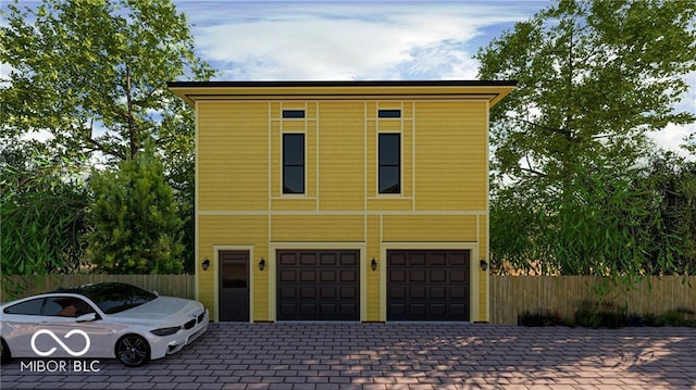 view of front of home with an attached garage, fence, and decorative driveway