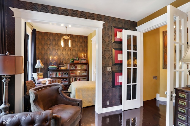 sitting room featuring a chandelier, baseboards, wood finished floors, and wallpapered walls