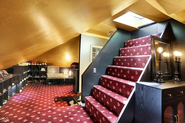 interior space with carpet floors and vaulted ceiling with skylight