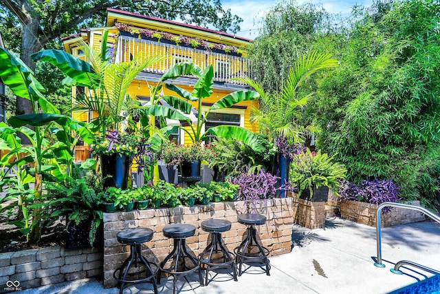 view of patio featuring outdoor dry bar and a balcony