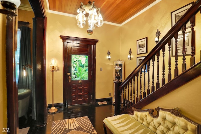 foyer entrance with wood ceiling, a notable chandelier, crown molding, and baseboards