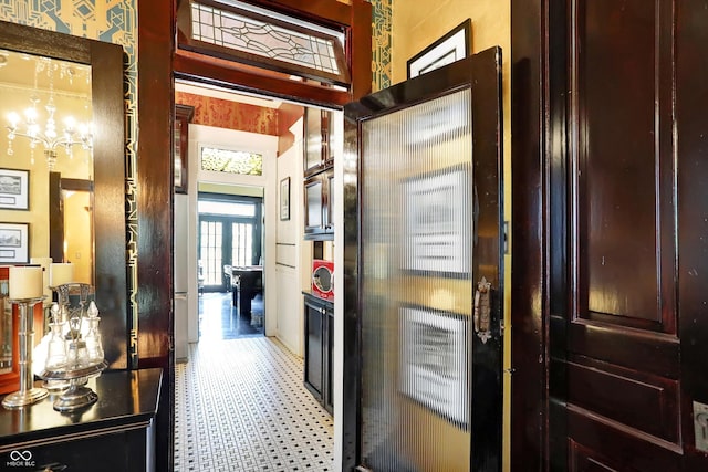 corridor with light floors and an inviting chandelier