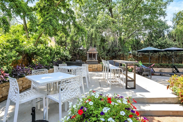 view of patio / terrace with outdoor dining space, fence, and an outdoor fireplace