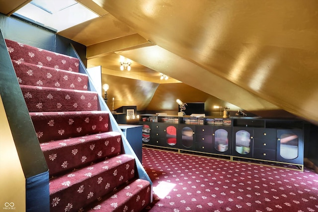 carpeted home theater featuring vaulted ceiling with skylight