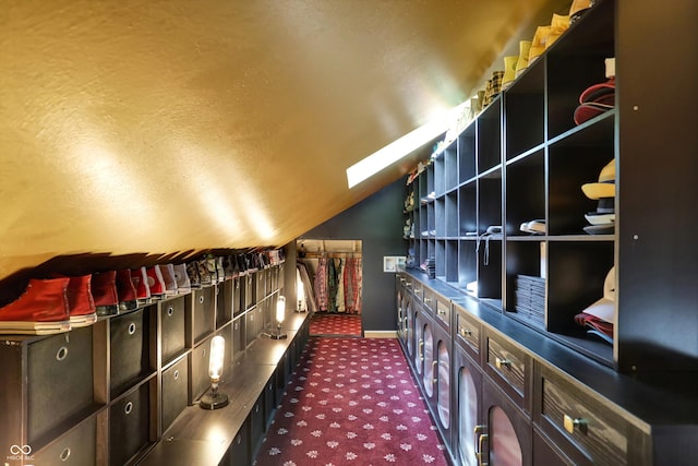 interior space with lofted ceiling with skylight and dark colored carpet