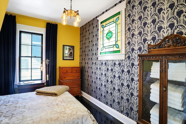 bedroom with a notable chandelier, wallpapered walls, multiple windows, and baseboards