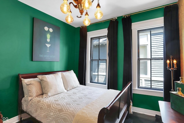 bedroom with an inviting chandelier, multiple windows, and baseboards