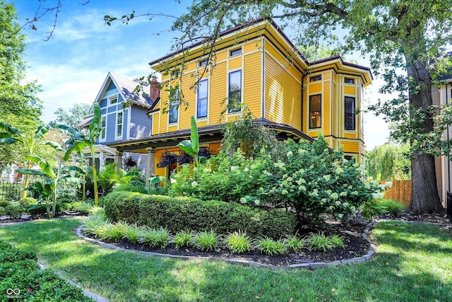 italianate-style house featuring fence and a front yard