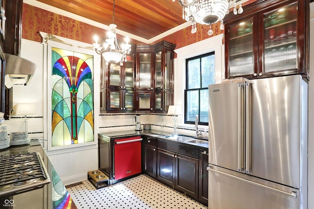 kitchen with high end fridge, hanging light fixtures, decorative backsplash, an inviting chandelier, and a sink