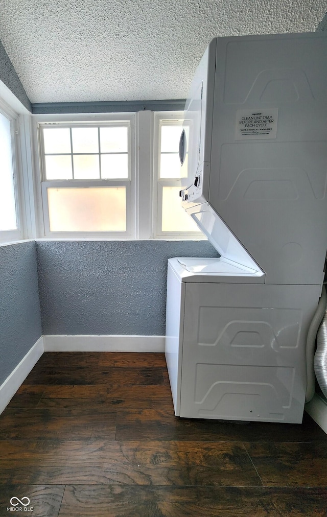 clothes washing area featuring a textured ceiling, a textured wall, laundry area, baseboards, and dark wood-style floors