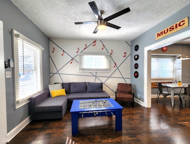 living room featuring dark wood-style floors, a ceiling fan, baseboards, and a textured ceiling