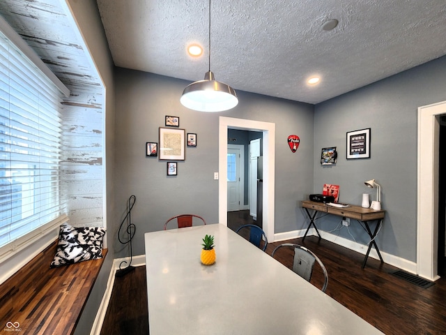 dining room with a textured ceiling, baseboards, and dark wood-type flooring