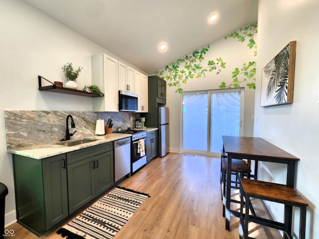 kitchen featuring a sink, white cabinetry, vaulted ceiling, appliances with stainless steel finishes, and open shelves