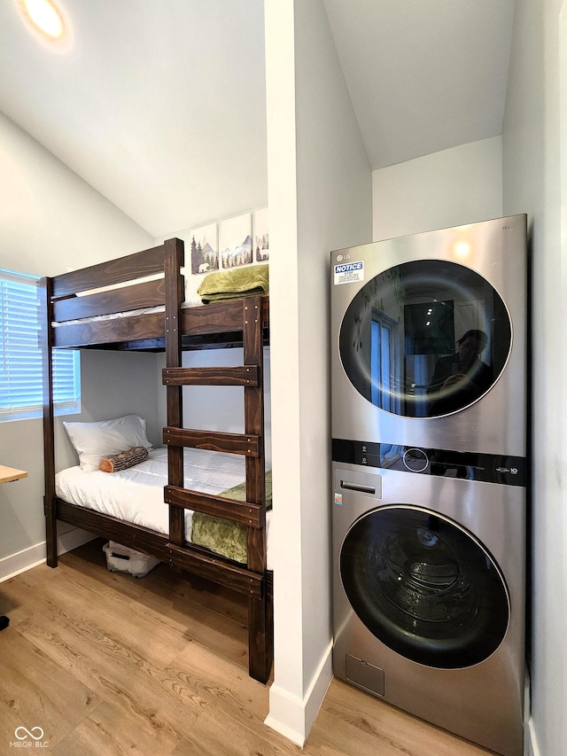 laundry room featuring light wood-type flooring, laundry area, baseboards, and stacked washer and clothes dryer