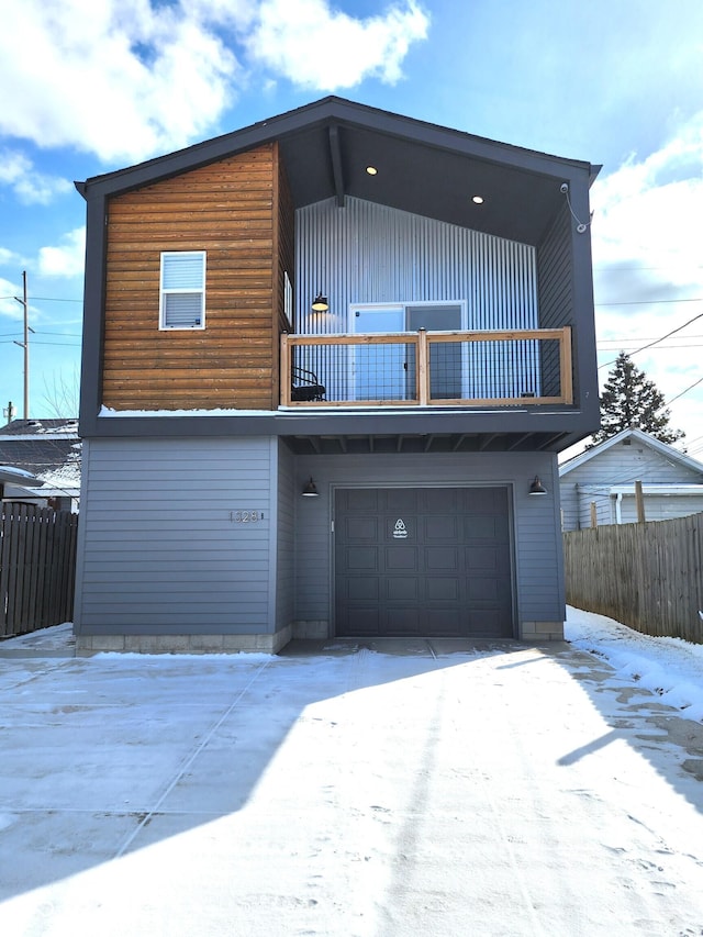 view of front of property with driveway, fence, a balcony, and an attached garage