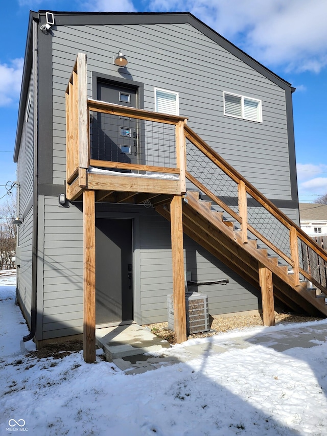 snow covered house with central AC and stairs