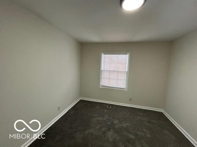 unfurnished room featuring baseboards, visible vents, and dark carpet