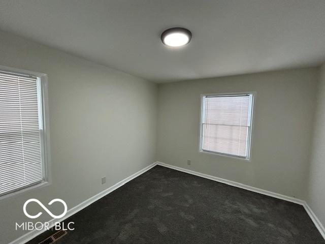 empty room with dark colored carpet and baseboards