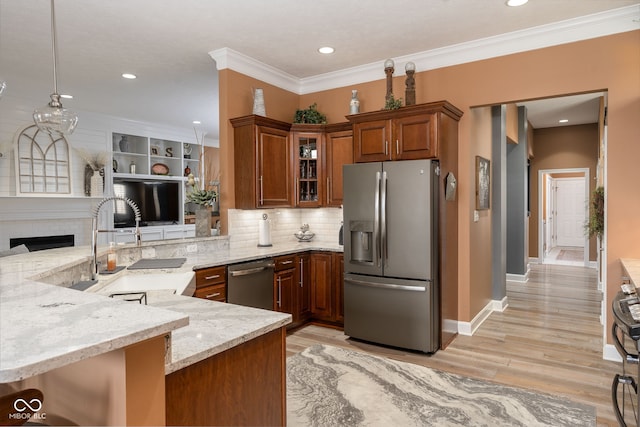 kitchen featuring appliances with stainless steel finishes, glass insert cabinets, a peninsula, and light stone counters