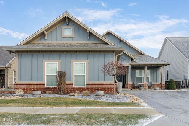 view of front facade with roof with shingles, board and batten siding, and brick siding