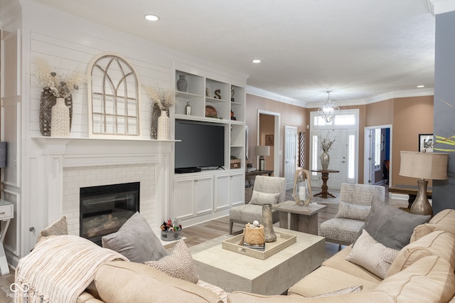 living room featuring ornamental molding, a fireplace, light wood-style flooring, and recessed lighting