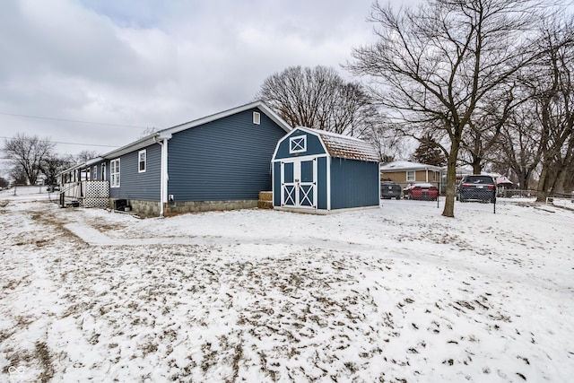 snow covered structure with a shed, an outdoor structure, and fence