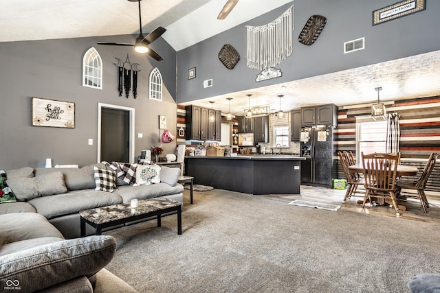 living area featuring high vaulted ceiling, light colored carpet, visible vents, and a ceiling fan