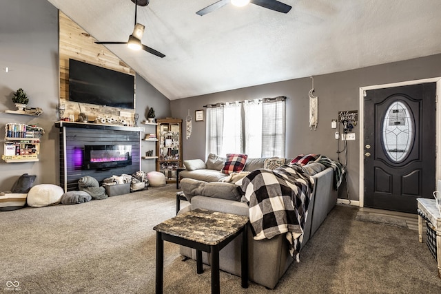 living area featuring dark colored carpet, lofted ceiling, a glass covered fireplace, ceiling fan, and a textured ceiling