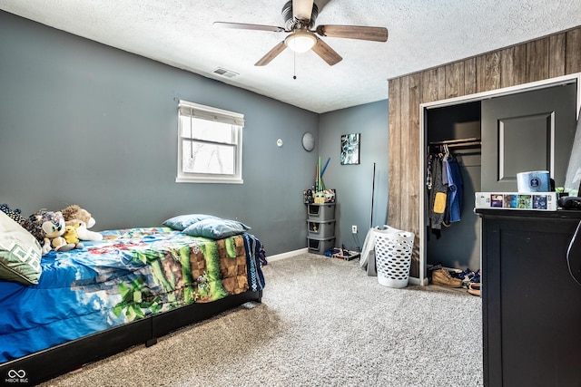 bedroom with a textured ceiling, ceiling fan, visible vents, a closet, and carpet