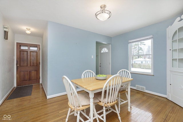 dining space featuring baseboards, visible vents, and light wood finished floors