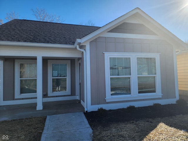 entrance to property featuring covered porch, board and batten siding, and roof with shingles