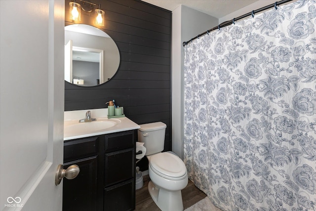 full bathroom with wooden walls, toilet, wood finished floors, curtained shower, and vanity