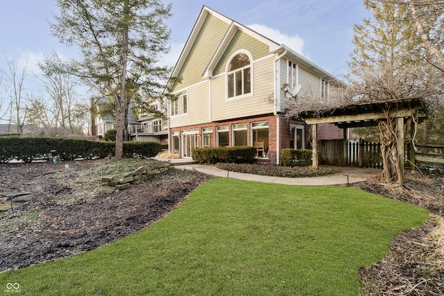 back of property with a yard, brick siding, and fence