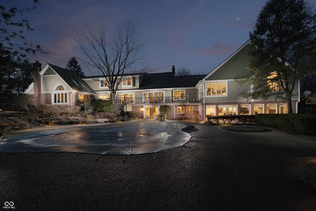 rear view of property with curved driveway and a chimney