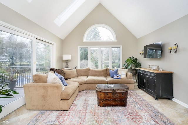 living room with light tile patterned floors, high vaulted ceiling, a skylight, and baseboards