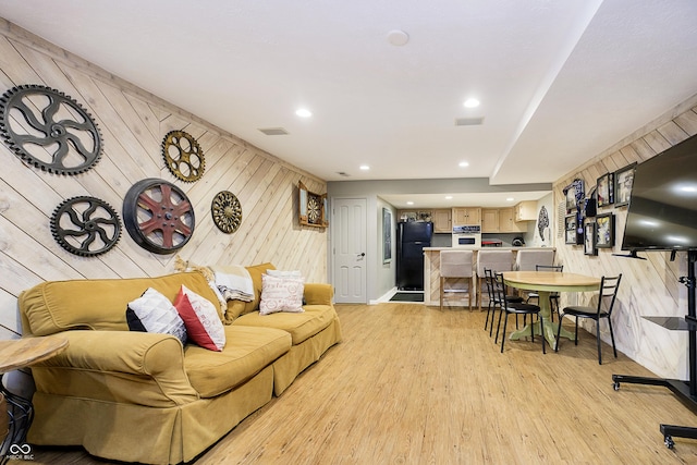 living room featuring wooden walls, recessed lighting, visible vents, and light wood-style flooring