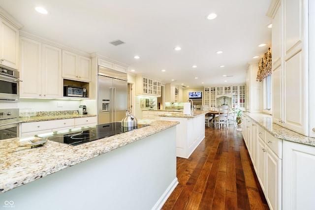 kitchen featuring stainless steel appliances, white cabinets, and light stone countertops