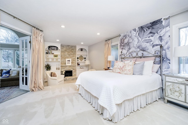 bedroom with access to outside, a stone fireplace, and recessed lighting