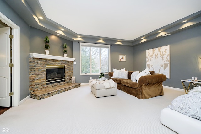 living room with carpet flooring, a stone fireplace, and baseboards