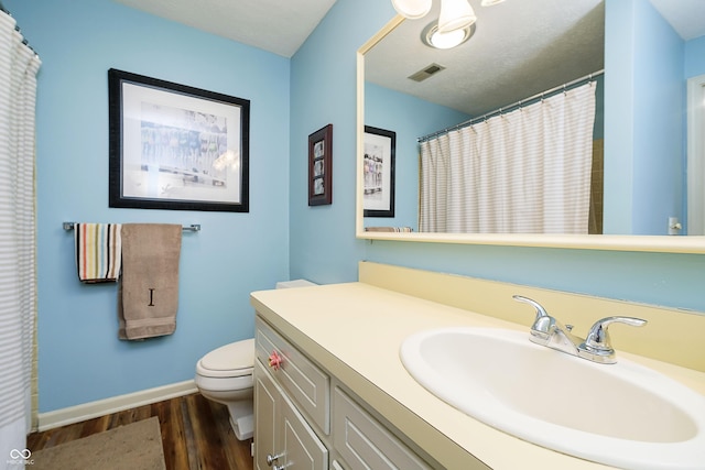 bathroom featuring visible vents, baseboards, toilet, wood finished floors, and vanity