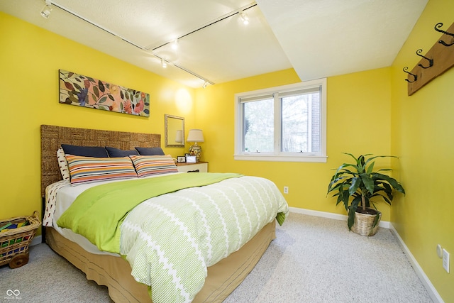 bedroom featuring light carpet, rail lighting, and baseboards