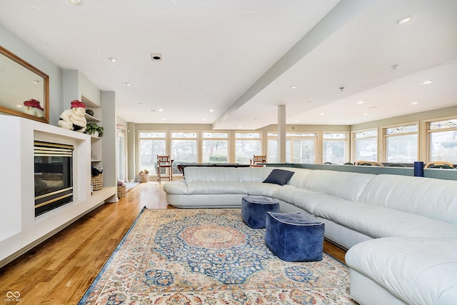 living area with recessed lighting, light wood-style flooring, built in shelves, and a glass covered fireplace