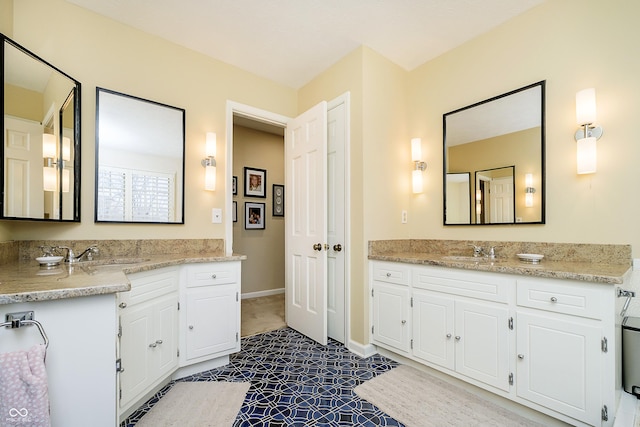 bathroom with two vanities, a sink, and baseboards