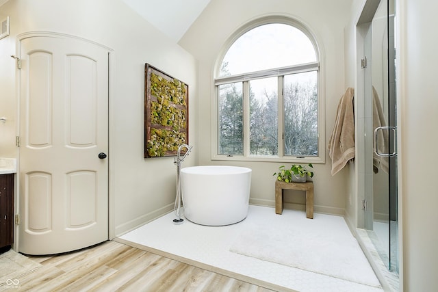 bathroom featuring visible vents, a freestanding bath, an enclosed shower, wood finished floors, and baseboards