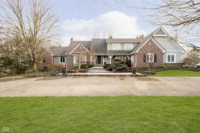 view of front of home featuring brick siding, a chimney, and a front lawn