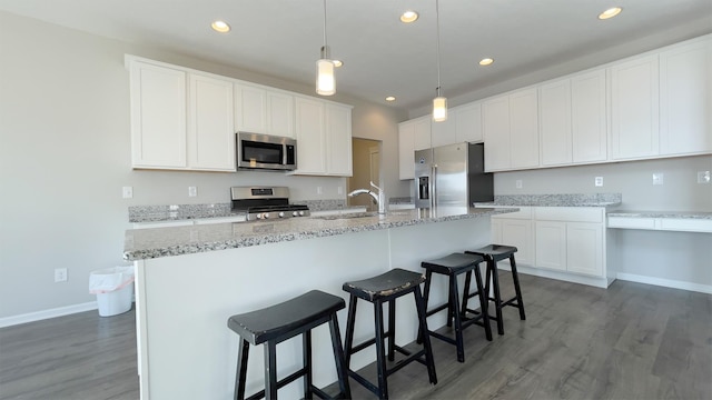 kitchen with wood finished floors, recessed lighting, a sink, appliances with stainless steel finishes, and white cabinetry