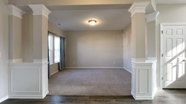 spare room with dark colored carpet, baseboards, dark wood finished floors, and ornate columns