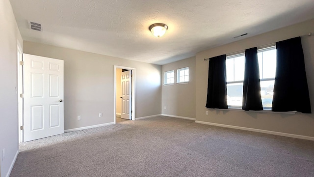 unfurnished room with baseboards, visible vents, carpet floors, and a textured ceiling